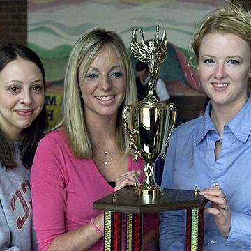 三名女学生拿着奖杯摆姿势.