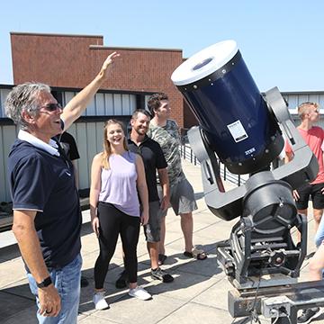 学生们在教室实验楼(CLB)屋顶的Paul Tebbe天文台查看望远镜。