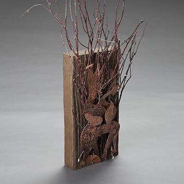 Metal sculpture of grass mounted on a block of wood