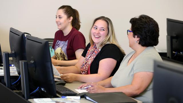 A Johnson County Community College instructor reviews diagnostic coding with two medical information and revenue management students.