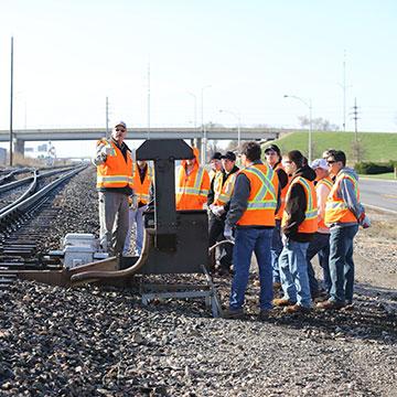 NARS students gather for an outdoor lesson along train tracks.