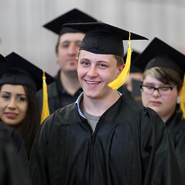 Man wearing cap and gown at GED graduation ceremony.