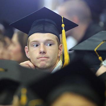 Man sitting among graduates at GED graduation ceremony.