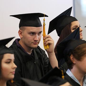 Man changing tassel at GED graduation ceremony.