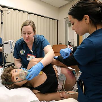 nursing students practice respiratory care on a simulation dummy