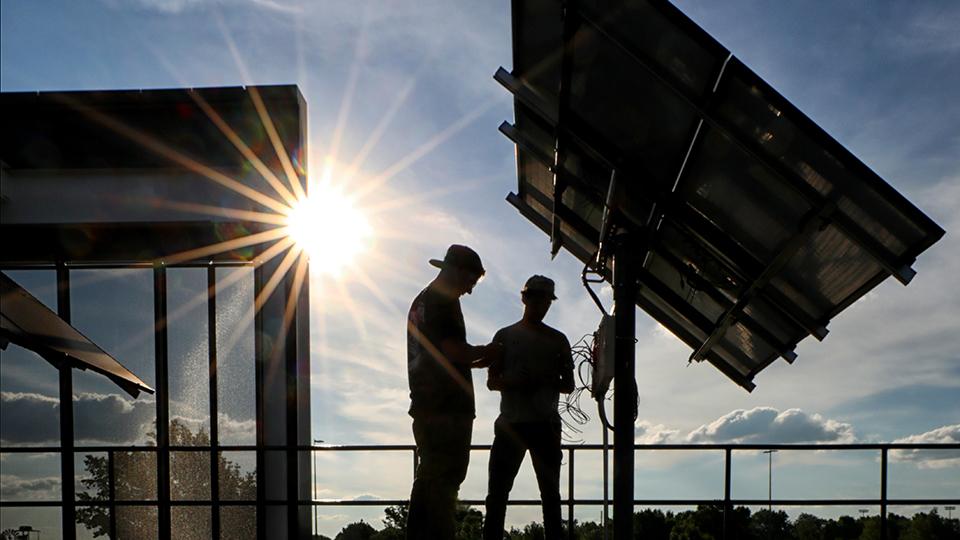 两名学生在CTEC外检查太阳能电池板