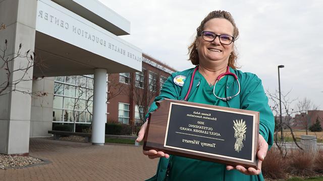 Tammy Wiemers holding her award as she stands outside the Olathe Health Education Center