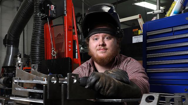 Colby Bunch sitting among tools in the welding lab