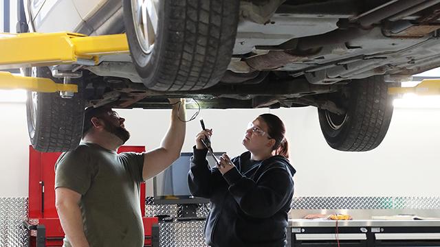 Female student working with instructor in the automotive lab
